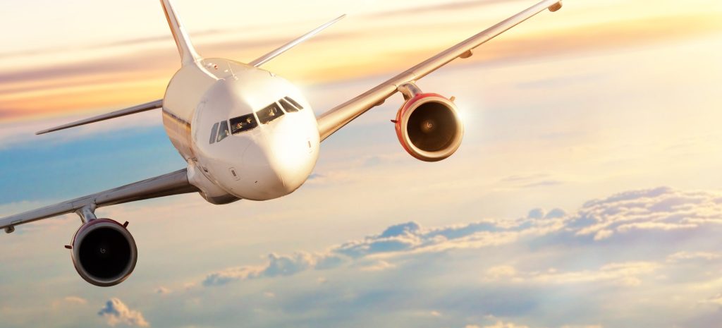 Airplane flying above clouds in dramatic sunset
